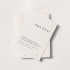 Minimalist wedding invitation card with serif typography, Alice & Joey names on ivory paper with envelope, modern elegant flat lay