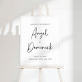 Minimal wedding welcome sign with clean serif typography displayed on a modern easel, featuring a soft off-white background and subtle natural shadowing.
