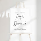 Minimal wedding welcome sign with clean serif typography displayed on a modern easel, featuring a soft off-white background and subtle natural shadowing.