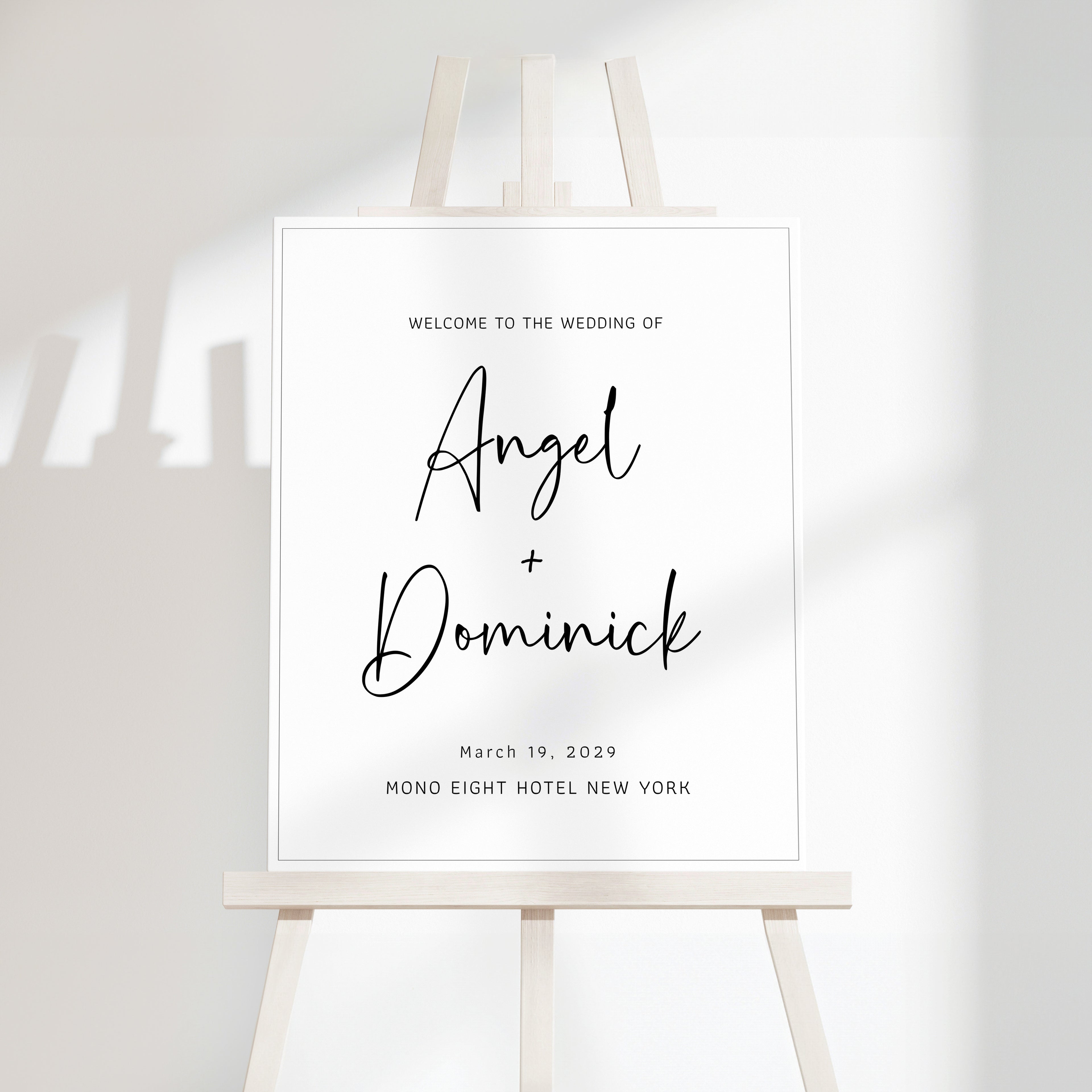 Minimal wedding welcome sign with clean serif typography displayed on a modern easel, featuring a soft off-white background and subtle natural shadowing.