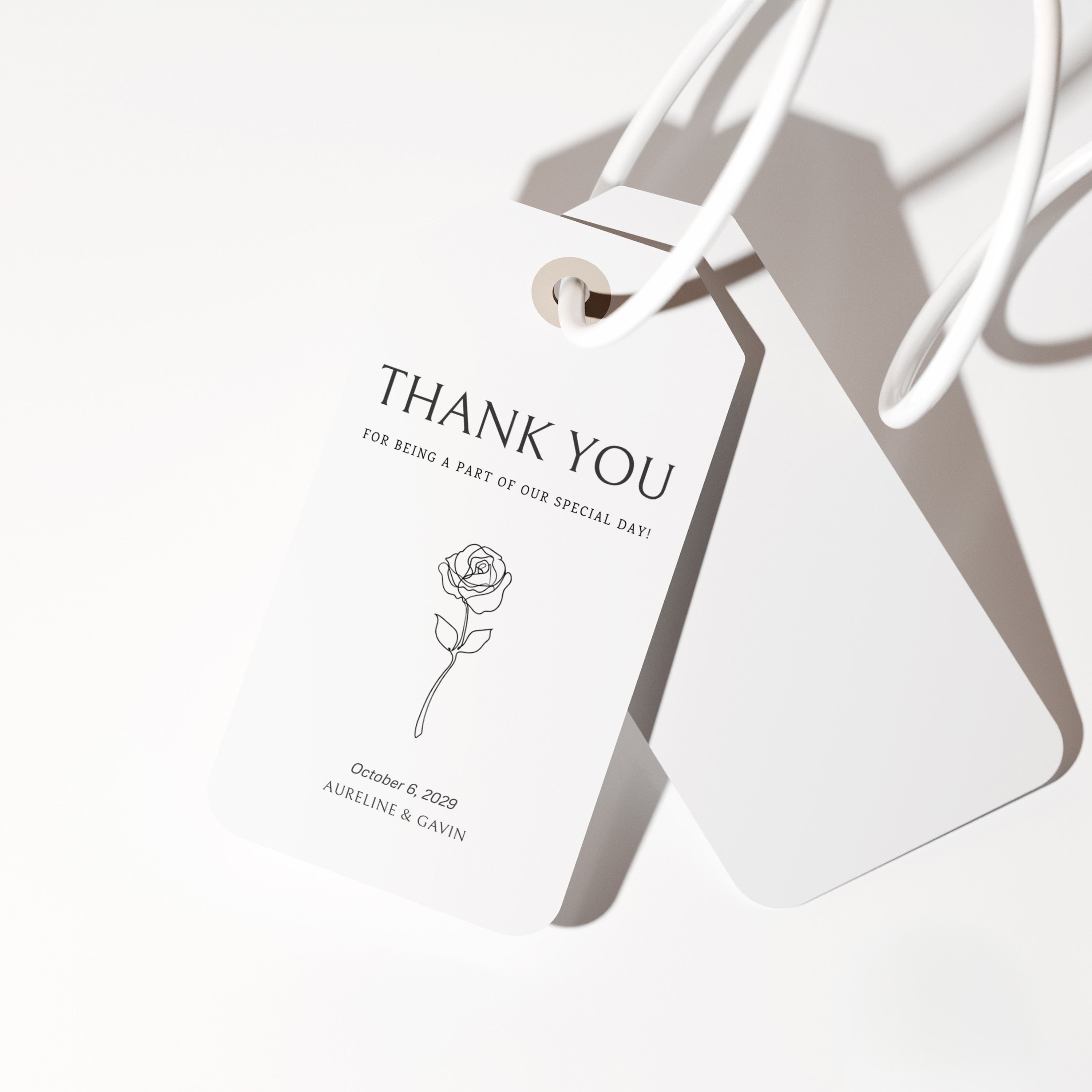 Minimal wedding favor tag featuring a refined serif thank you message, a delicate floral line illustration, and a soft natural shadow.