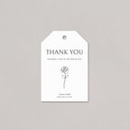 Elegant wedding favor tag with clean serif typography, a simple floral line detail, and a smooth white cord on a light background.