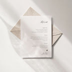 Minimal editorial wedding menu featuring a right-aligned layout with the script title “Let’s eat,” printed on off-white paper and styled with a textured envelope in soft natural light.