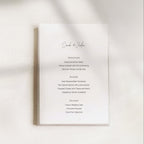 Minimal wedding menu design with centered typography, featuring a clean white card layout, refined serif text, and a softly lit neutral background, styled for an elegant modern wedding table
