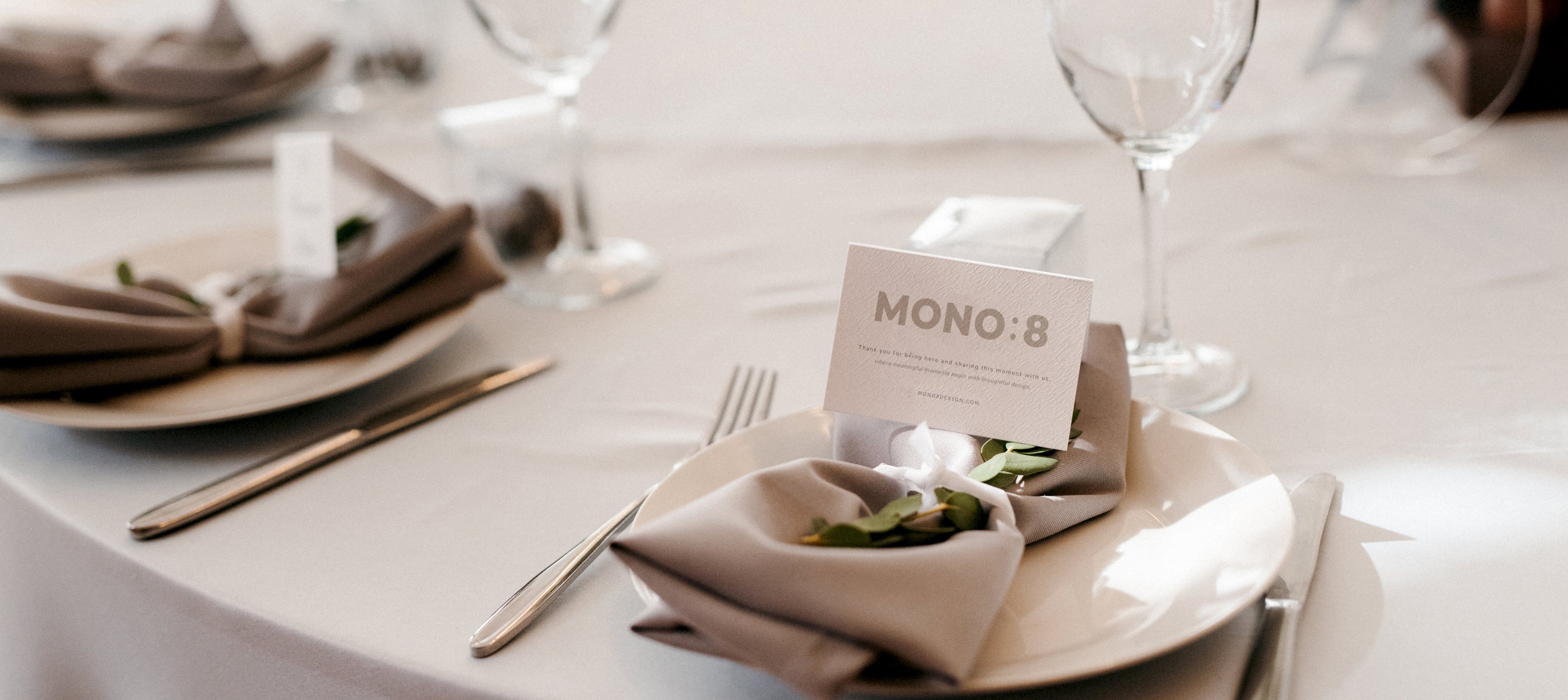Elegant table setting with a 'MONO:8' card on a white tablecloth.